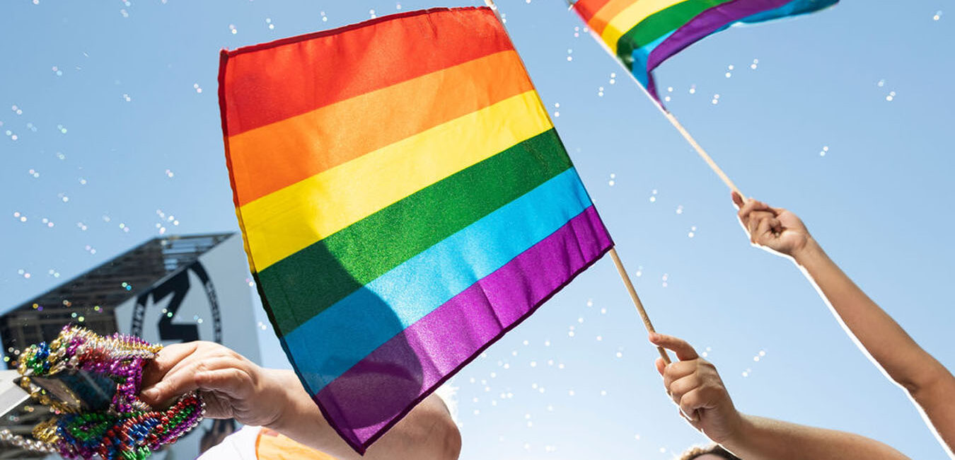 The LGBTQ Flag being waved by someone on a float