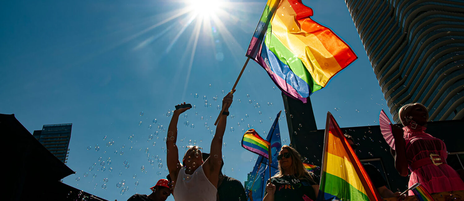 A person waving a LGBTQ flag on a float