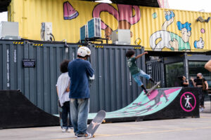 two skateboarders are looking at skateboarder on the ramp