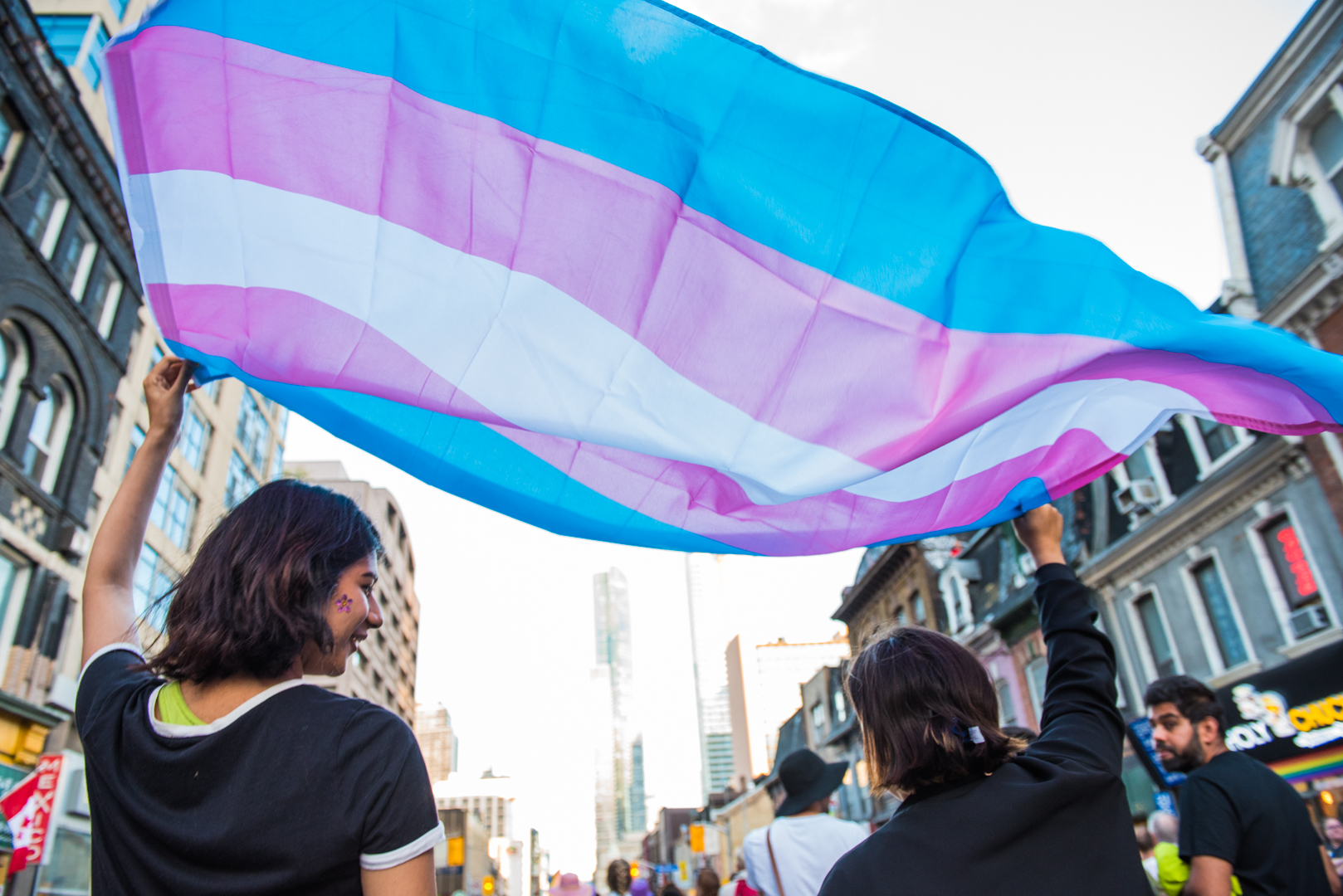 Two people holding the Tran Flag on top of their heads in the air