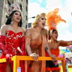 three drag queens leaning from a float.