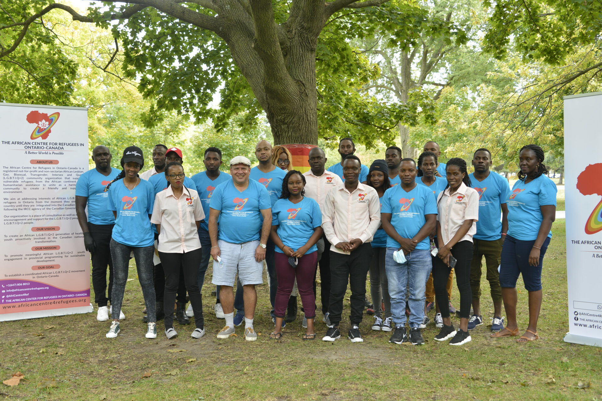 A group of volunteers and staff from the African Centre for Refugees standing together in a park