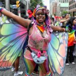 a festival goer in the parade dressed with butterfly wings