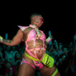 a performing in a neon pink swim outfit dancing in front of a crowd